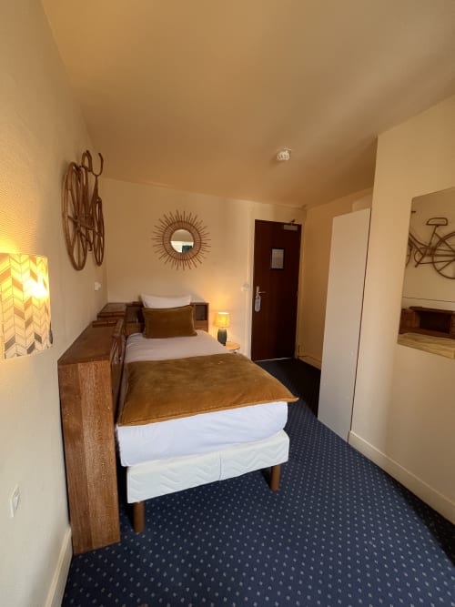 Single room at Hotel Le Trouville in Trouville-sur-Mer with wooden bed, warm lighting, and city view