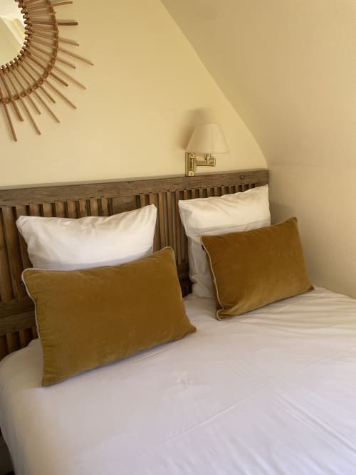 Double bed with gold cushions and white pillows at Hotel Le Trouville, Trouville sur Mer, featuring wooden headboard and