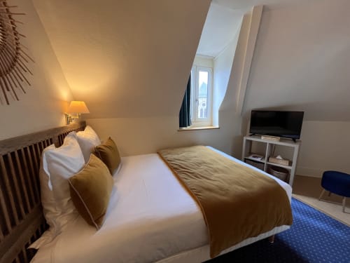 Cozy double bedroom at Hotel Le Trouville with TV, desk, and landmark view from window in Trouville sur Mer