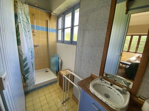 Bright bathroom in Le Gîte de la Fresque Interdite cottage at Le Lama Zébré B&B, Penmarch, with shower, sink, and garden