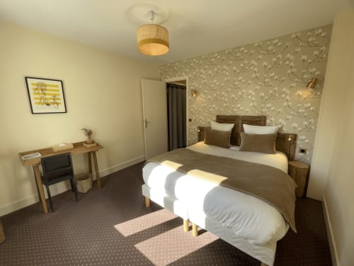 Comfortable double bedroom at Hotel Le Trouville with floral wallpaper, wooden furniture, and city view in Trouville sur Mer