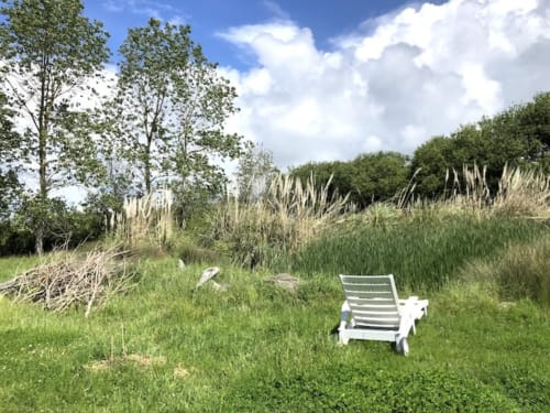 White lounge chair in lush garden at Le Lama Zébré cottage in Penmarch, France