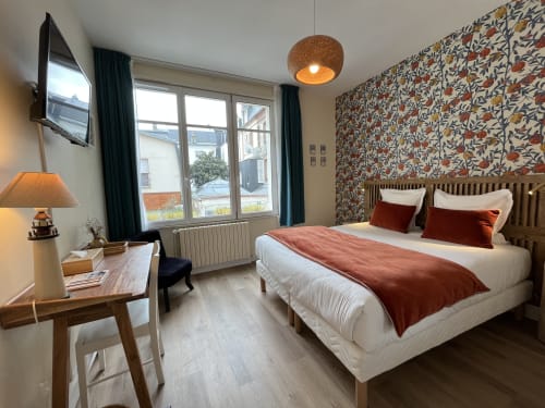 Comfortable double bedroom at Hotel Le Trouville with floral wallpaper, city view, flat-screen TV, and modern amenities in