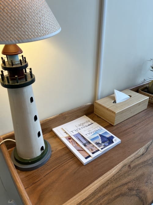 Hotel Le Trouville room decor with lighthouse figurine, magazines, and tissue box on wooden nightstand