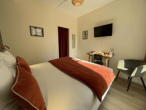 Modern double bedroom at Hotel Le Trouville in Trouville sur Mer with red accent décor, flat-screen TV, desk, and city view