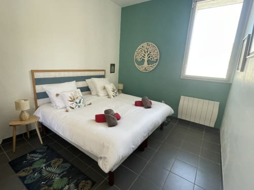 Chambre moderne aux Prairies du Val d'Amboise à Noizay avec mur accent bleu-vert, lit en bois et serviettes jumelées
