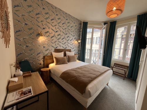 Comfortable double bedroom at Hotel Le Trouville with balcony overlooking Trouville-sur-Mer, bird-patterned wallpaper, and