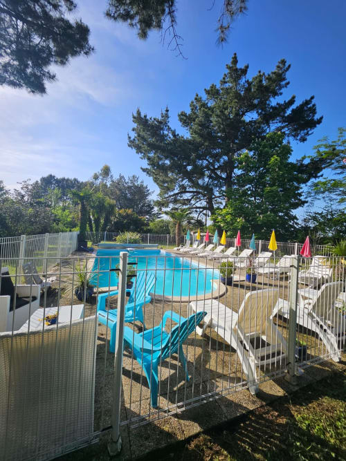 Glitzerndes blaues Schwimmbecken im Ferienhaus Le Manoir Lacustre in Queyrac mit Liegestühlen und farbigen Sonnenschirmen