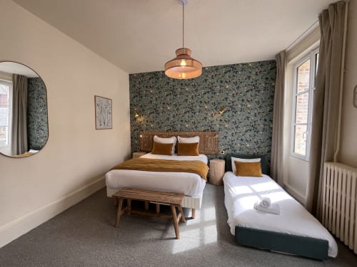 Modern triple bedroom at Hotel Le Trouville with dual beds, patterned accent wall, wooden furniture and city views