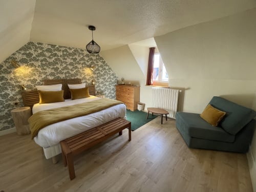 Spacious hotel bedroom with floral headboard, wooden furniture, and green sofa at Hotel Le Trouville, Trouville sur Mer