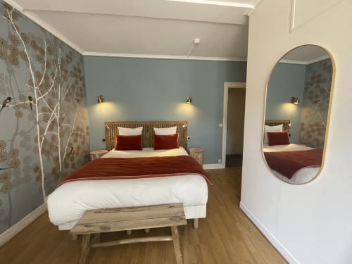 Modern bedroom at Hotel Le Trouville with blue accent wall, red bedding, wooden bench, and oval mirror
