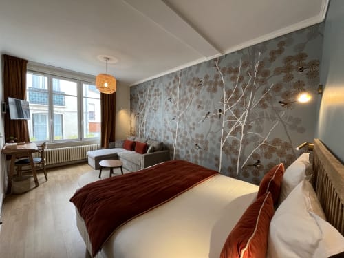 Modern junior suite at Hotel Le Trouville with bed, sofa seating, decorative wallpaper and city views of Trouville sur Mer