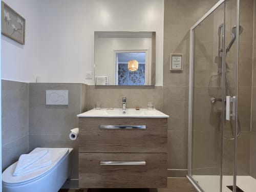 Modern bathroom in Hotel Le Trouville suite with floating vanity, walk-in shower, and illuminated mirror overlooking city