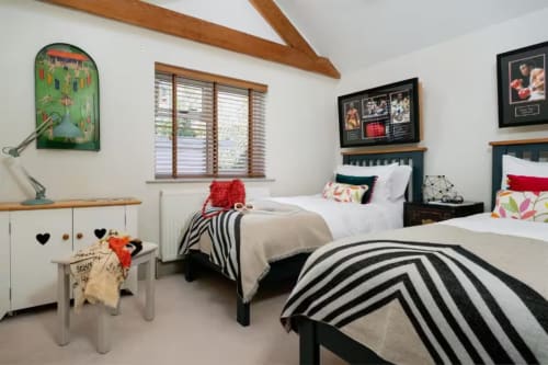 Bright twin bedroom at 2 Doves Holiday Property in Exeter with black beds, striped blankets, colorful cushions and wooden