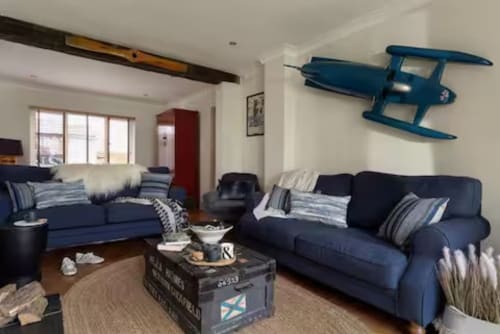 Modern living room at 2 Doves Holiday Property in Exeter with dual navy sofas, blue airplane wall art, and nautical décor