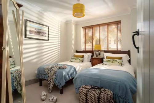 Twin bedroom at 2 Doves Holiday Property in Exeter with blue bedding, yellow accents, and wooden shutters.