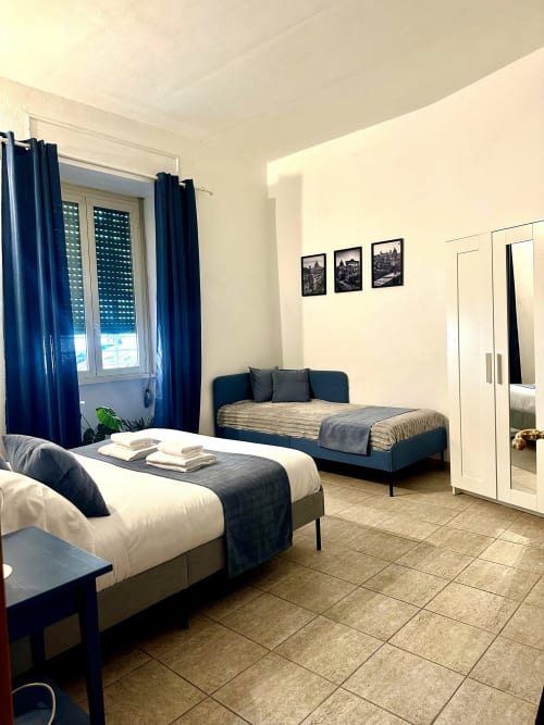 Nowoczesny apartament studyjny w Rzymie z dwoma łóżkami, niebieskimi akcentami, podłogą z płytek i widokami na miasto z okna
