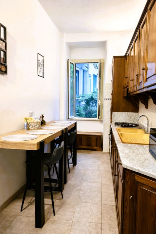 Nowoczesna kuchnia z drewnianymi szafkami, blatami marmurowymi i wyspą z miejscami do siedzenia w apartamencie RomeAntique Stay, Rzym