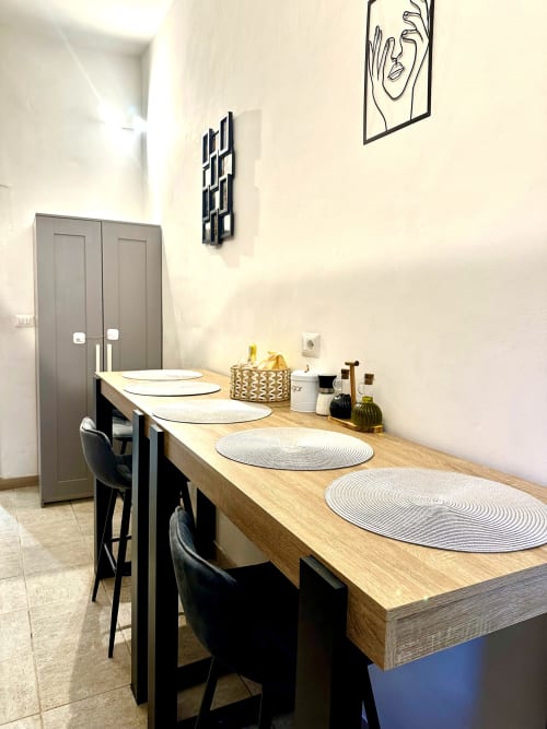 Nowoczesna jadalnia w apartamencie RomeAntique Stay z drewnianym stołem, czarnymi krzesłami i współczesną sztuką ścienną w Rzymie