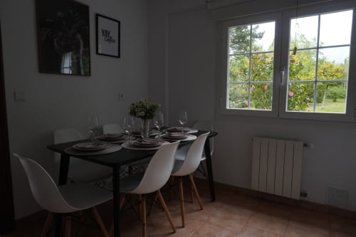 Comedor moderno en Bizkar Bare con mesa negra, sillas blancas, puesta de mesa y vistas a las montañas a través de grandes ventanales