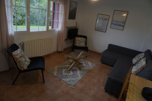 Sala de estar moderna del apartamento Bizkar Bare en Vizcaya con asientos negros, mesa de cristal y vistas al jardín