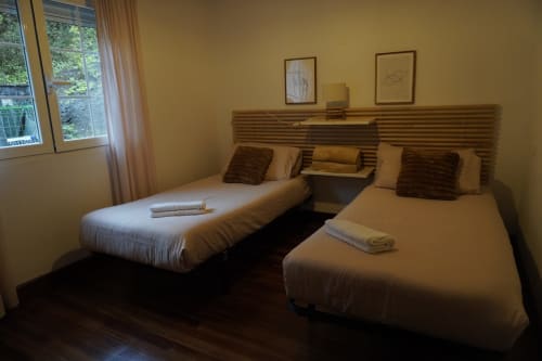 Habitación doble en apartamento Bizkar Bare en Vizcaya con dos camas, cabecero de madera y ventana con vista al jardín