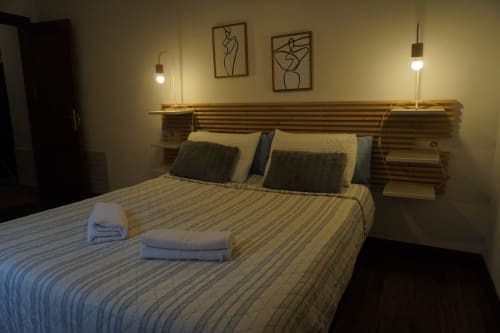 Dormitorio moderno del hotel Bizkar Bare en Vizcaya con ropa de cama a rayas, cabecero de madera, lámparas colgantes y arte mural abstracto