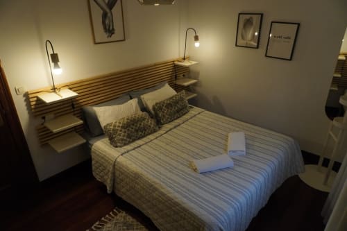 Dormitorio moderno en el hotel Bizkar Bare de Vizcaya con ropa de cama a rayas, cabecero de madera y iluminación contemporánea