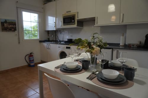 Cocina y zona de comedor modernas del apartamento Bizkar Bare en Vizcaya, mesa preparada con cubiertos y flores frescas