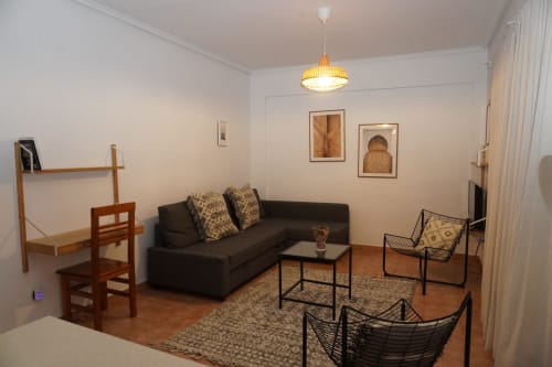 Sala de estar del apartamento Bizkar Bare con sofá negro, lámpara colgante moderna y vistas al jardín en Vizcaya
