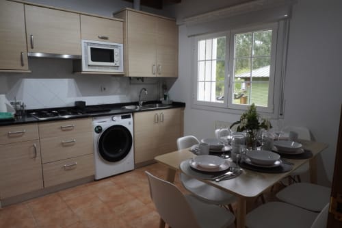 Moderna zona cocina-comedor del apartamento Bizkar Bare en Vizcaya con armarios de madera, encimeras negras y mesa de comedor