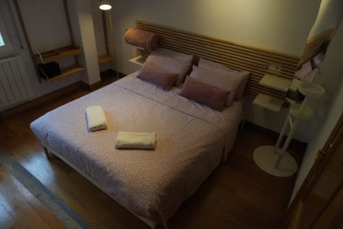 Dormitorio del apartamento Bizkar Bare en Vizcaya con cama doble, cabecero de madera, almohadas marrones y amenities de bienvenida