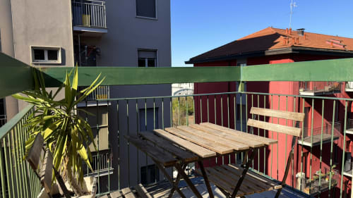 Balcone soleggiato in città presso AirFlat Opera con tavolo in legno, ringhiere verdi e edifici adiacenti