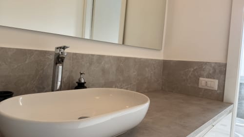 Vanità moderna del bagno con lavabo bianco ovale e rivestimento in marmo grigio dell'appartamento Opera
