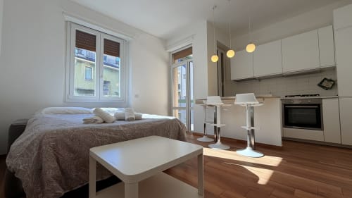 Monolocale moderno presso AirFlat Opera con letto, cucina, zona pranzo, pavimenti in legno e vista sulla città