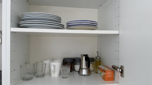 Ripiani di credenza in cucina nell'appartamento Nessa's Home con piatti, bicchieri e elettrodomestici a Opera