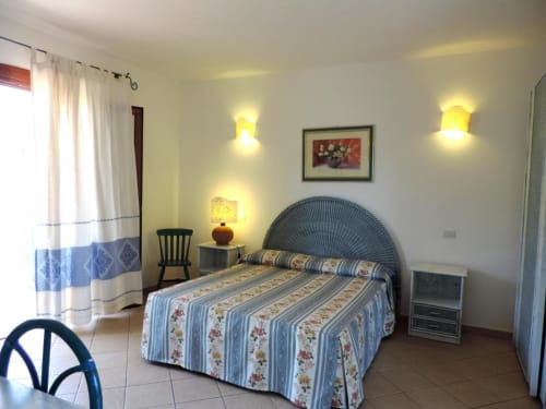 Camera quadrupla luminosa all'Hotel Domu Incantada a Muravera con biancheria a righe, testata con ventilatore e illuminazione calda