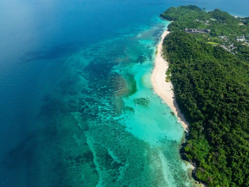 Vue aérienne du lagon turquoise et plage de sable blanc bordés de jungle verdoyante, Mamoudzou Mayotte