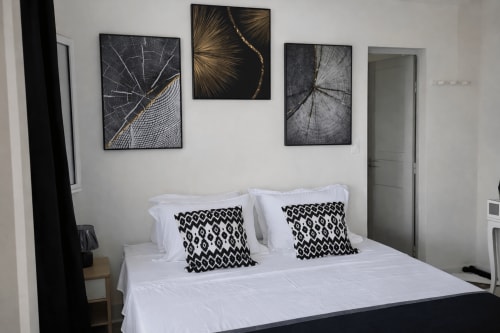 Chambre moderne à la Kaz Kafe guesthouse de Mamoudzou : literie blanche, oreillers à motifs noirs et décoration murale inspirée de la nature