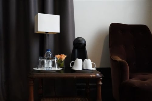 Detalhe do quarto no B&B Quinta de Anterronde em Arouca com mesa-de-cabeceira, luminária, água, serviço de café e cadeira.