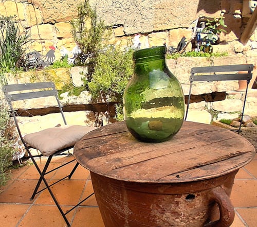Rústica zona de comedor al aire libre en RuralGorgs de El Vilosell con mesa de madera, sillas plegables y jarra de vidrio verde