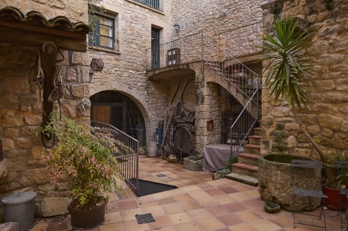 Patio histórico de piedra en RuralGorgs, El Vilosell, con arcos, suelo de terracota y plantas en macetas