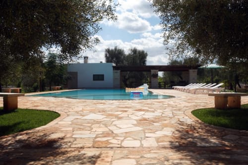 Area piscina Trulli Boccadoro con terrazza in pietra, sdraie e moderna struttura bianca in Puglia