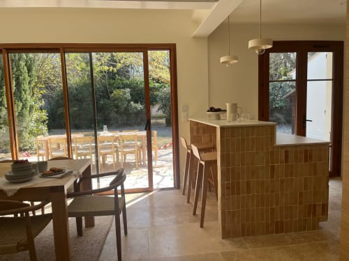 Cuisine et salle à manger modernes avec vue sur le jardin à Soleù, mobilier en bois, luminaires suspendus et terrasse