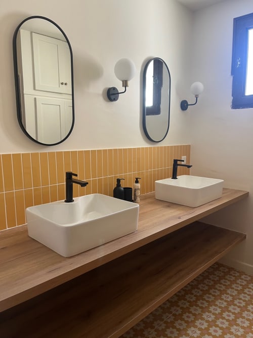 Salle de bain double vasque moderne avec vasques blanches, robinetterie noire, plan de travail bois, dosseret carrelage jaune