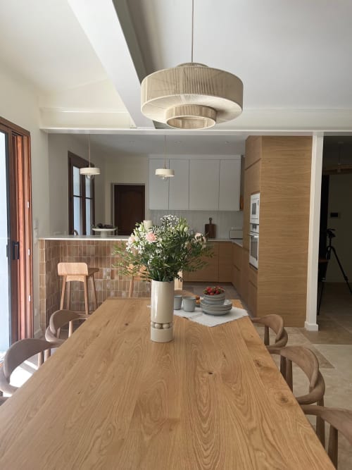 Élégante cuisine ouverte à la villa Soleù avec table en bois, suspensions blanches et vue sur le jardin