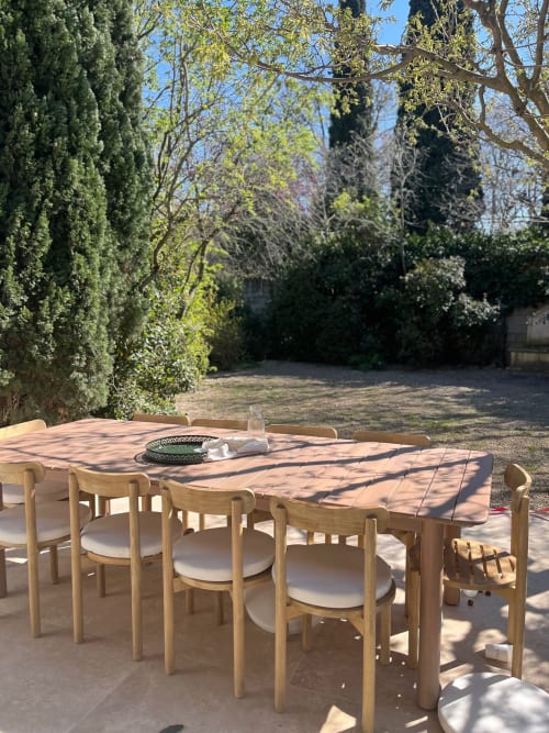 Espace de restauration en plein air dans le jardin provençal de la villa Soleù, avec table et chaises en bois sous les cyprès