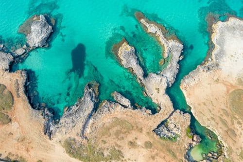 Acque turchesi costiere e scogliere calcaree presso Trulli Boccadoro, Italia, vista aerea della riva rocciosa e spiaggia sabbiosa