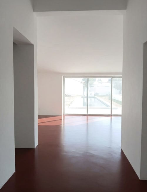 Elegante interior minimalista da villa em Alentejo33 com pisos escuros polidos, paredes brancas e portas de vidro com vista para São