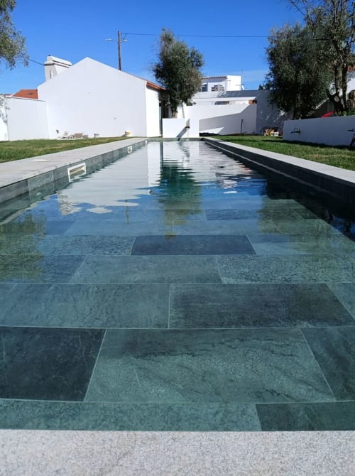 Piscina de borda infinita com pavimento em pedra turquesa na villa alentejo33 em Arraiolos, Portugal, cercada por edifícios brancos e